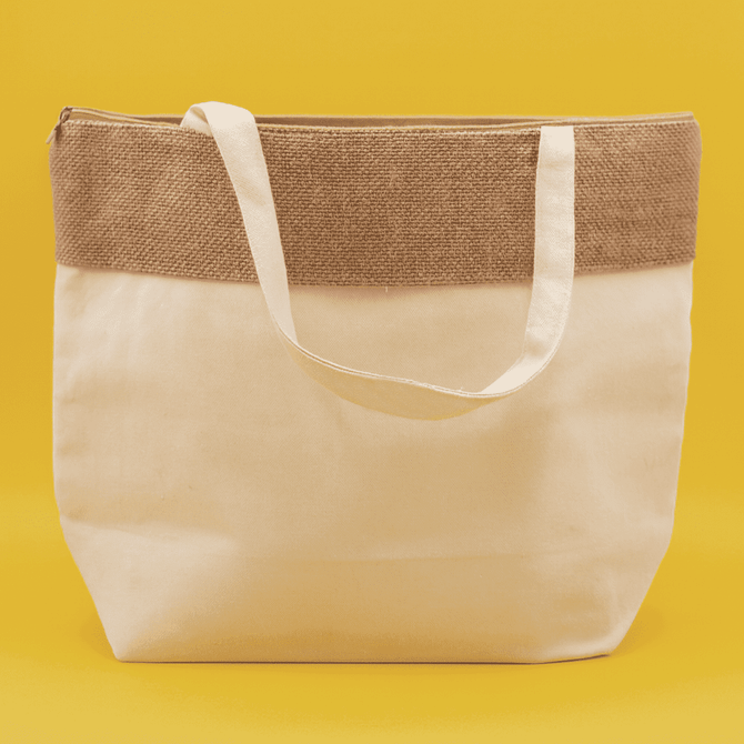 A jute and cotton cooler bag in cream with a brown jute top and white straps, featuring a logo.