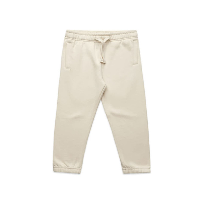 Cream-coloured kids' track pants featuring an elasticated waistband and side pockets. The pants have a logo detail.