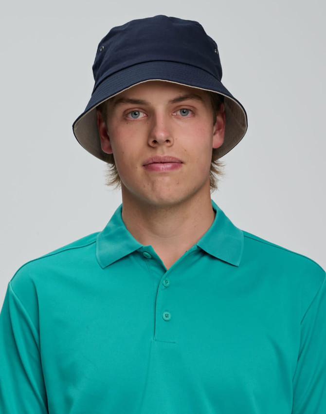 A contrasting underbrim bucket hat in navy, featuring a light-coloured underbrim, worn with a teal polo shirt.