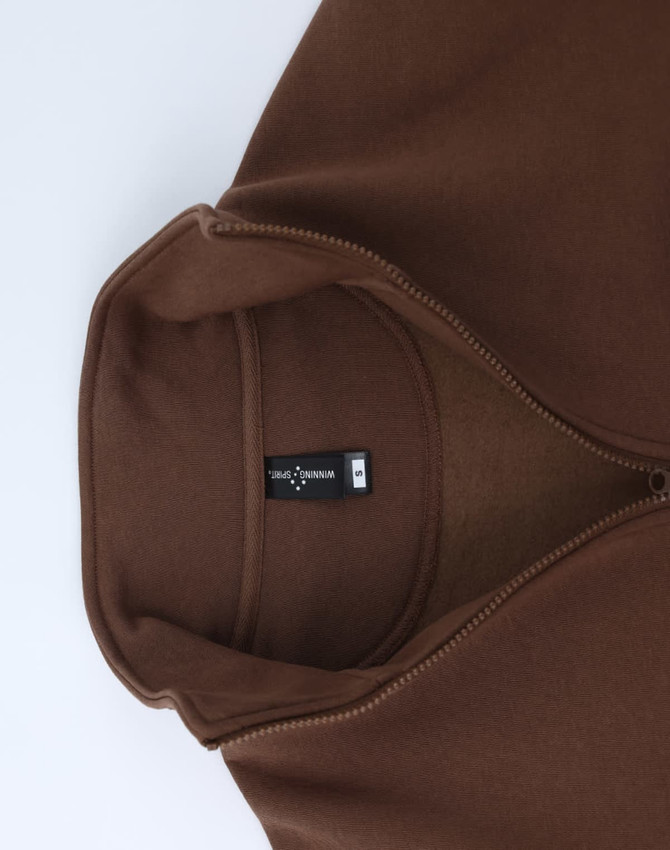 A brown polar fleece jumper featuring a 1/2 zip collar and an internal label. It has a smooth, soft texture.