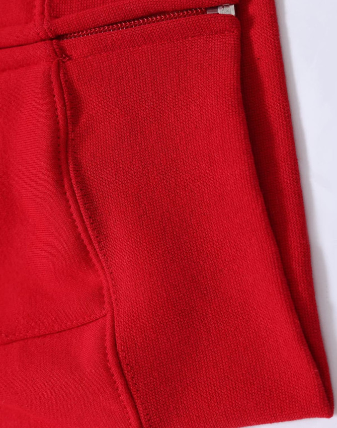 A close-up of a red fleecy hoodie featuring a full-zip and zippered pocket. The fabric appears soft and textured.