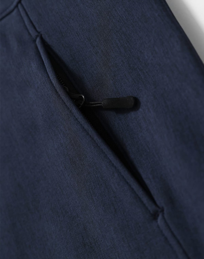 A close-up of a navy blue softshell hoodie featuring a zippered pocket. The fabric has a soft texture.