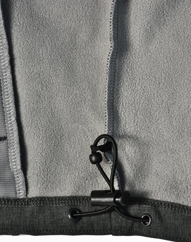 A grey softshell full zip hoodie featuring a drawstring toggle and fleece interior. It has a logo on the fabric.