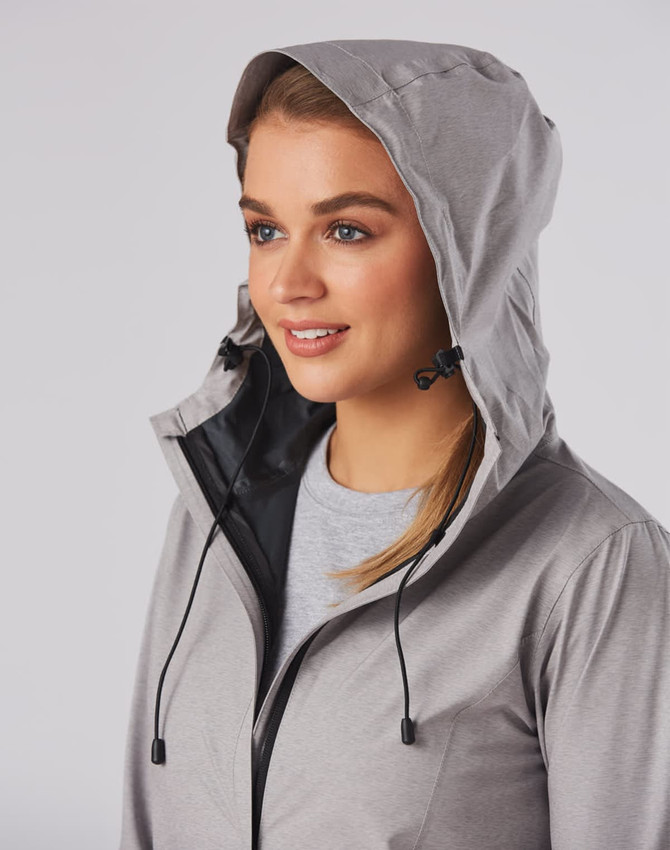 A grey waterproof performance jacket featured on a model, showcasing a hood and drawstring detail.