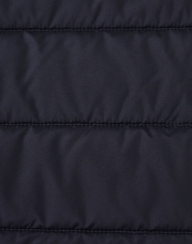 A close-up of a navy blue insulated puffer jacket fabric with a stitched, quilted pattern and a logo.