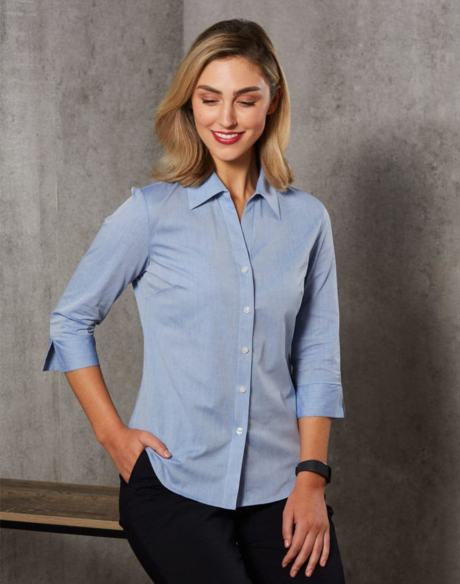 A women's fine chambray shirt in light blue with 3/4 sleeves and a button-up design, featuring a logo.