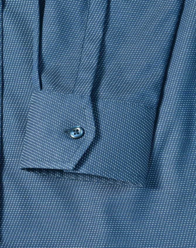 A close-up of a blue pin dot stretch long-sleeve shirt featuring a buttoned cuff and a patterned fabric.