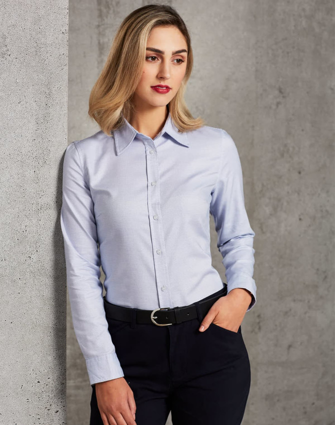 A long-sleeve button-up shirt in light blue, featuring a collar and a fitted design, paired with dark trousers.