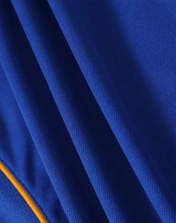 A close-up of a blue polo shirt with textured fabric and yellow accents, featuring a logo.