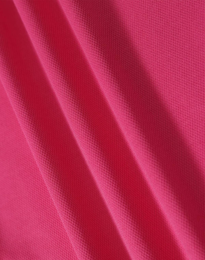 A close-up of textured fabric in a vibrant pink colour, showcasing its structure and weave.