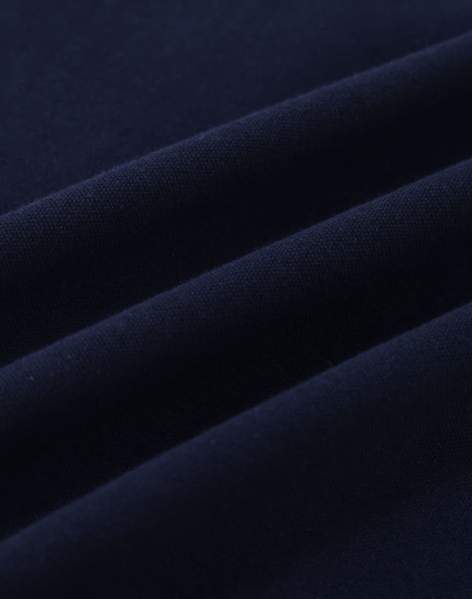 A close-up of navy cotton fabric with visible stretch and texture, ideal for polo shirts.