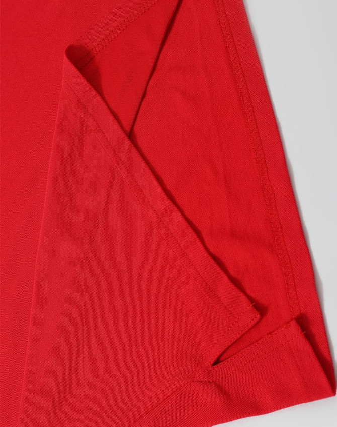 A red Men's Truedry Pique Polo shirt, showcasing its smooth fabric and detailed stitching. The shirt has a logo.