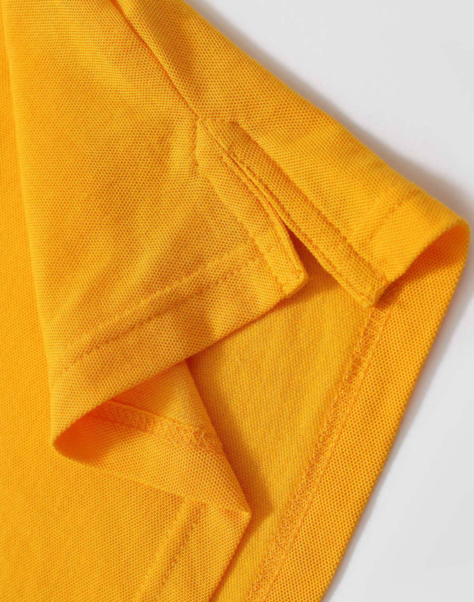 A close-up of a folded yellow polo shirt, highlighting the collar and sleeve details. The fabric appears textured and vibrant.