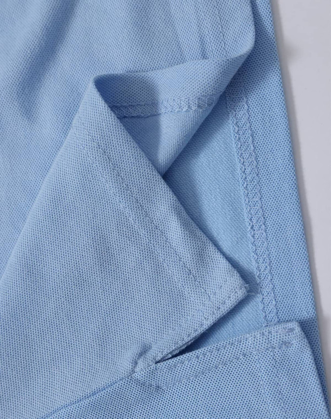 A close-up of a light blue polo shirt, highlighting the fabric texture and stitching details. The shirt features a logo.