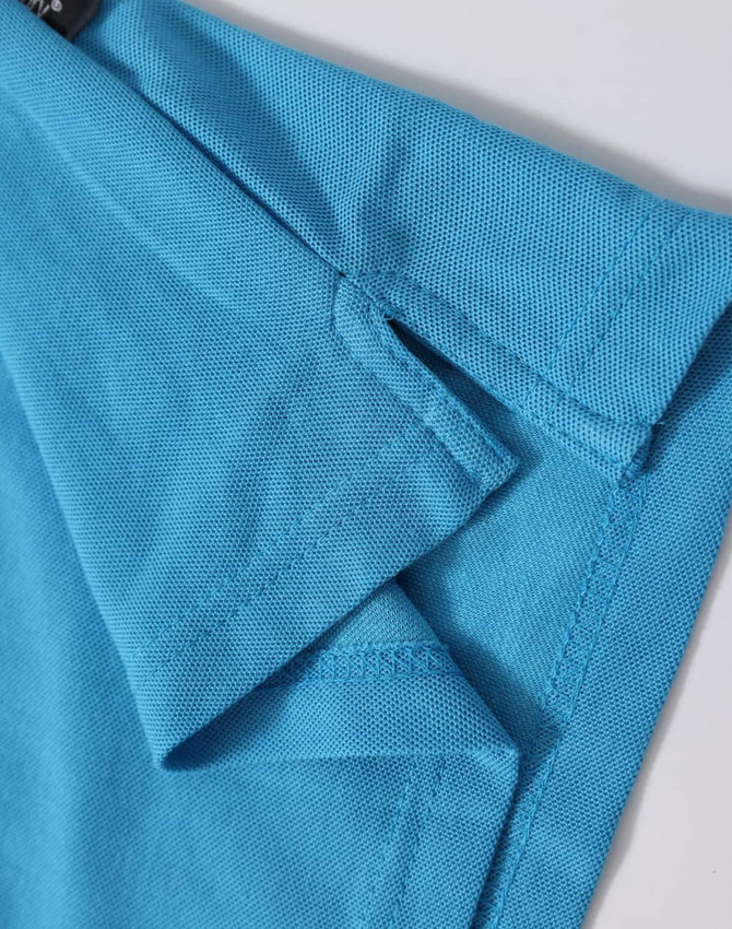 A close-up of a turquoise polo shirt, featuring a branded label and detailed fabric texture.