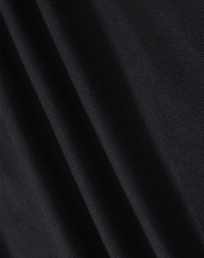 A close-up of black fabric showcasing the texture of a polo shirt. The material appears smooth and lightweight.