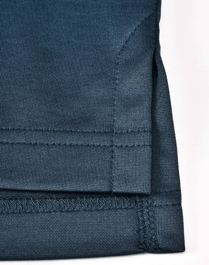 A dark teal men's sustainable poly/cotton polo shirt, showcased with a focus on the hem and sleeve detailing.