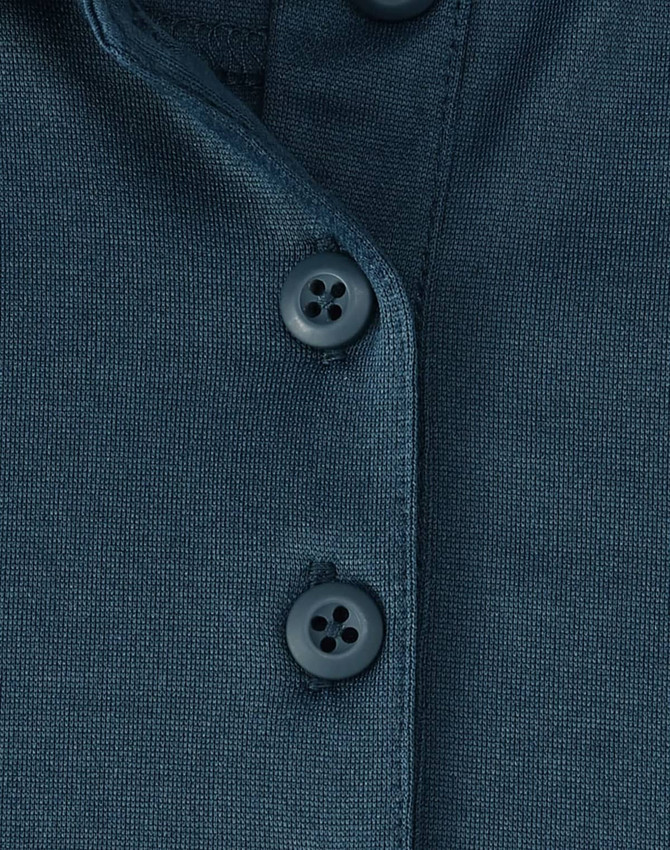 A close-up of a dark teal polo shirt featuring three buttons and a textured fabric. The shirt has a logo.