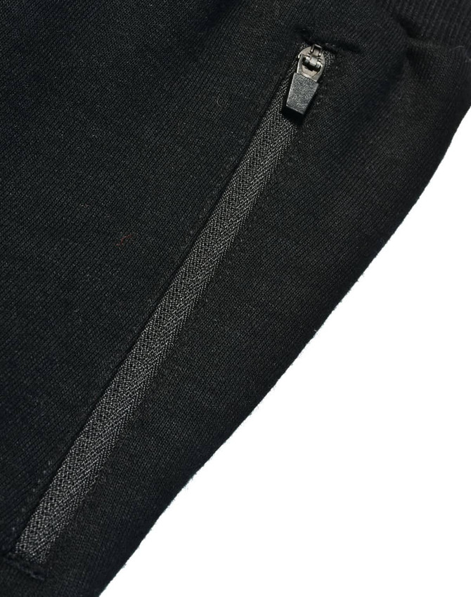 A close-up of black kids' poly/cotton terry sweat pants featuring a zippered pocket.