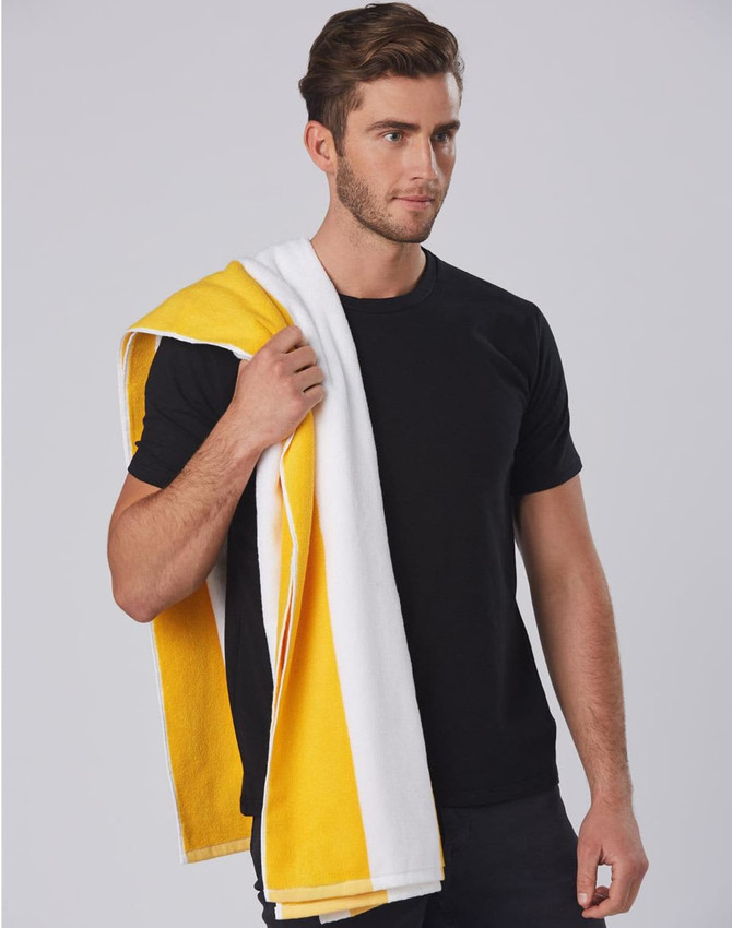 A striped beach towel in yellow and white draped over one shoulder, held by a person wearing a black t-shirt.