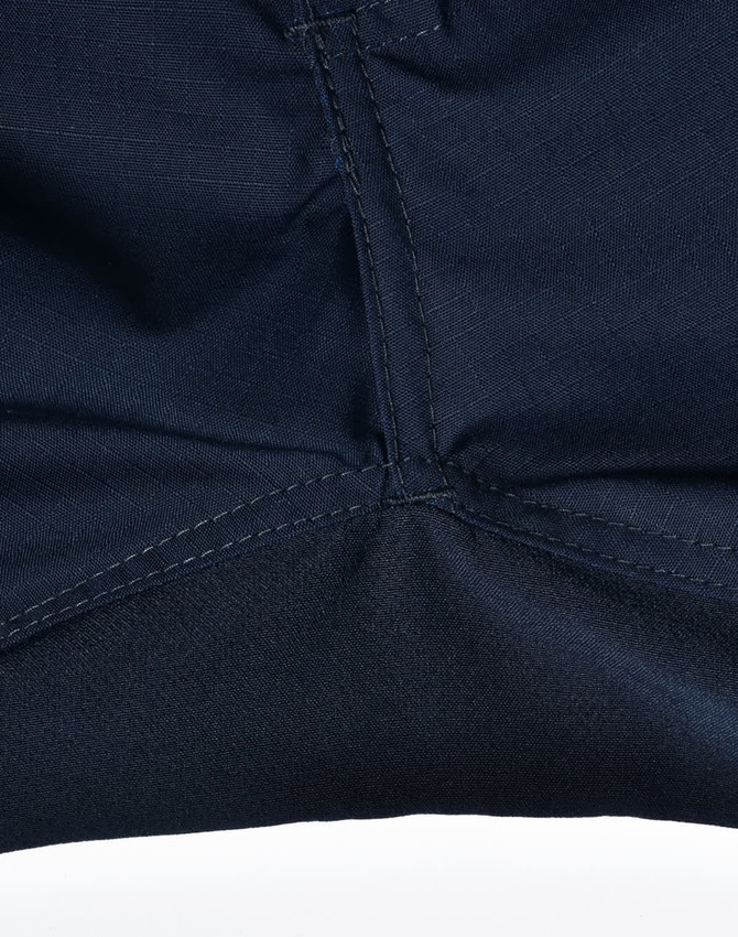 Close-up of navy rip-stop poly/cotton stretch work pants, highlighting the stitching detail and fabric texture.