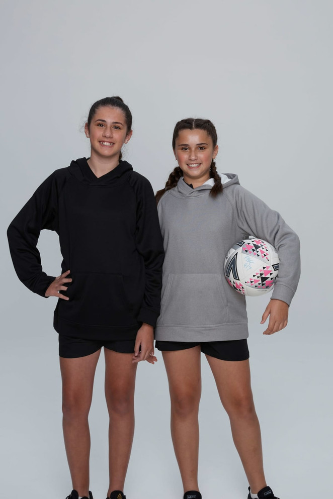 Two girls wearing hoodies, one black and one grey, stand together. One girl holds a patterned ball.