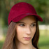 A burgundy cap with a curved brim and a logo on the front, worn by a person outdoors.