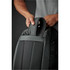A dark green duffle bag with a padded handle, being held by a person's hand. The bag features mesh panels.