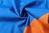 A close-up of fabric featuring vibrant blue and orange tones, showcasing a smooth, soft texture.