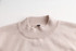 A unisex 100% cotton crew neck sweater in a soft beige colour, featuring a ribbed collar and a simple logo.