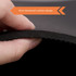 A hand holding the edge of a black yoga mat, highlighting its 6mm thick cushion design.