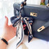 A silk chiffon scarf in navy, featuring a floral pattern, tied elegantly to a black handbag.