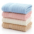 A stack of bamboo fiber towels in blue, pink, cream, and beige, neatly folded with a textured design.