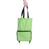 A green collapsible shopping trolley bag with black accents and a front pocket, held by a hand.