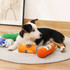 A dog lies on a soft rug surrounded by colourful squeaky can-shaped pet toys in orange, green, and blue.