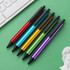 A selection of six plastic click pens in red, blue, yellow, green, and purple, with black tips and grips.