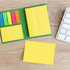 A compact sticky notepad with yellow pages and colourful sticky flags, placed on a wooden surface beside a keyboard.