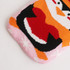 A hot water bottle with a knitted penguin cover in pink, red, black, and white hues, featuring a playful design.