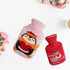 A hot water bottle features a pink penguin knitted cover alongside a red reindeer cover, surrounded by flowers.