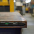 A magnetic torpedo level in black rests on a metal surface, featuring a liquid vial for measuring.