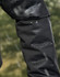 A close-up of a black waterproof jacket sleeve with droplets of water beading on the surface.