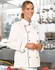 A Unisex Executive Chef Jacket in white with black accents, modelled by a smiling individual in a kitchen setting.