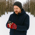Fingerless gloves in red and blue, worn by a man using a smartphone, set in a snowy outdoor environment.