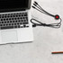 A black 3-in-1 charging cable with multiple connectors rests beside a laptop on a marble surface.