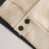 A close-up of a unisex varsity jacket featuring a cream and navy design with black buttons.