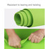 A green TPE yoga mat, rolled tightly with hands gripping the edge, showcasing its flexibility and durability.