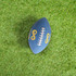 A blue American football with a logo on one side, resting on a green grass surface.