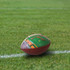 A promotional American football featuring a field design, placed on green grass with white lines. It has a logo.