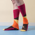 Mid-calf custom pattern socks featuring vibrant colours: pink, orange, yellow, and brown, with a logo on the foot. Mid-calf custom pattern socks featuring vibrant colours: pink, orange, yellow, and brown, with a logo on the foot.