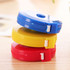 A stack of three round tape measures in blue, yellow, and red, each featuring a small white clip.